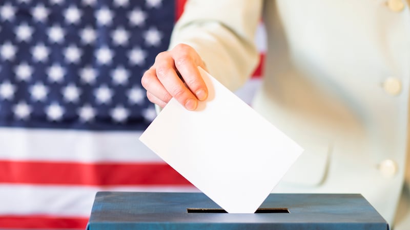 FILE - Woman putting ballot in box.